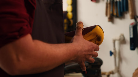Carpenter putting sandpaper on piece of plastic, creating abrasive sponge to smooth surfaces. Man preparing necessary gear for furniture assembling job in studio, close up shot.の写真素材