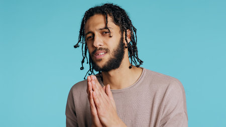 Guy asking for forgiveness, putting hands together in imploring gesturing, showing regret emotion. Upset man saying sorry, begging for apology, feeling guilty, studio background.の写真素材