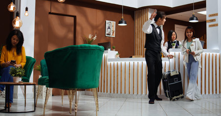 After check in process, receptionist handing over passport and key for room access at five star hotel. Professional employee providing great services for guest at front desk, confirming id papers.の写真素材