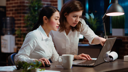Asian employee brainstorming with coworker to compose email at computer desk, finalizing deal with business partners. Businesswoman and colleague closing agreement with associates, camera Bの写真素材