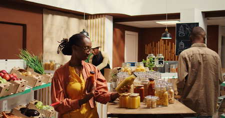 African american buyer putting pasta and organic sauce in a basket, choosing vegan ethically sourced food alternatives. Woman buying eco friendly natural products from local grocery store. Camera 2.の写真素材
