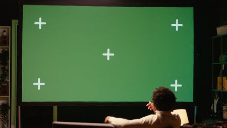 Man using streaming services on ultrawide chroma key TV to binge watch series from the comfort of his apartment. Cord cutter enjoying shows on television set during leisure time on couchの写真素材