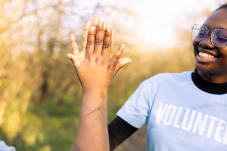 Team of female environmentalists doing high five after a job well done, congratulating and showing praise to each other. Pleased motivated people enjoying their successful mission.の写真素材