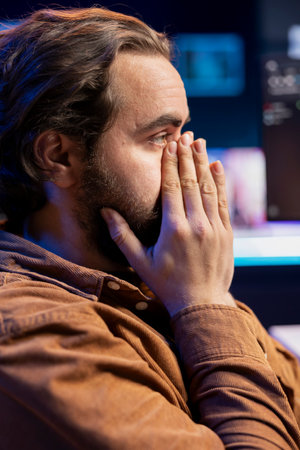 Worried cybersecurity expert putting face in hands after finding many security vulnerabilities, scared of malware infections. Anxious developer distressed by cyber attacks on computer systemsの写真素材