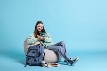 Teenager reading messages on phone, feeling delighted after receiving good news. Woman excited by SMS on smartphone, isolated over studio backgroundの写真素材