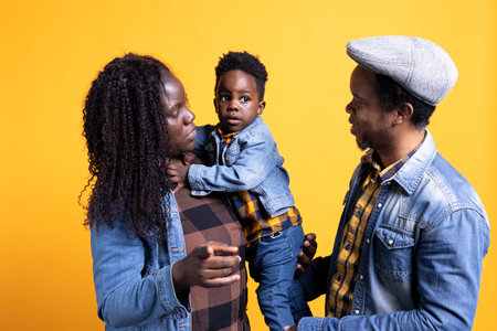 Portrait of african american family with a little child posing on camera, showing gratitude and sympathy towards each other and feeling satisfied. Happy mom and dad holding their boy.の写真素材
