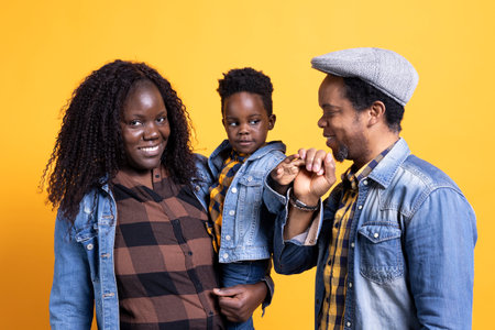 African american happy family posing together on camera, smiling couple embracing their small baby boy. Cheerful young mom and dad showing affection to their toddler in studio.の写真素材