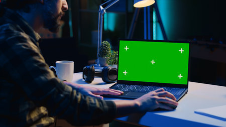 Teleworker in living room office using chroma key laptop to analyze sales report and plan business development. Remote worker doing project research, typing on green screen device keyboardの写真素材