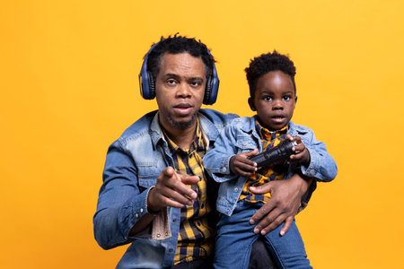 Loving father wearing headset and holding his small child on camera, smiling and having fun with his young son. Cute toddler playing with a flashlight, affectionate parent with his kid.の写真素材