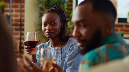 African american woman at apartment party watching man share interesting story, having crush on him. Guest at home gathering in love with charming BIPOC host captivating friends with taleの写真素材