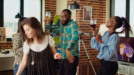 Diverse mix of guests at home party sharing laughter and dance moves in living room, holding wine glasses in hand. Smiling friends dancing on lively beats during weekend hangout, shaking hipsの写真素材