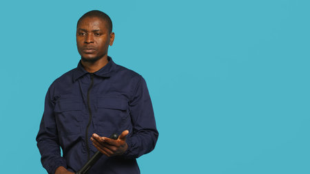 Security guard holding baton, posing for a portrait in a studio background. Camera A.