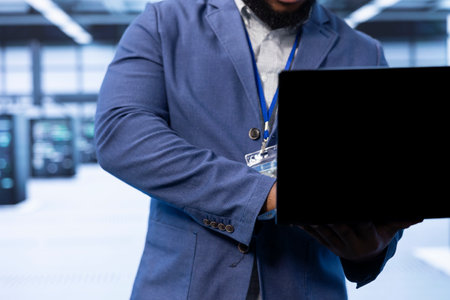 Admin walking in data center, using laptop to configure network infrastructure such as routers,...