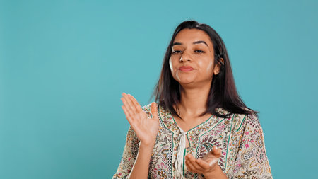 Portrait of woman mockingly clapping hands, showing frustration, studio backdrop. Resentful person rolling eyes and applauding in jest, feeling irritated, camera Bの写真素材