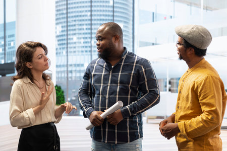 Corporate team discussing their vision with the realtor expert, reviewing architectural plans for a new office space to relocate the startup business. Potential real estate investment opportunity.の写真素材