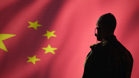 Military dispatcher working for Chinese army relaying info for troops using headset. Radio communications operator isolated over China flag background coordinating soldiers through headphonesの写真素材