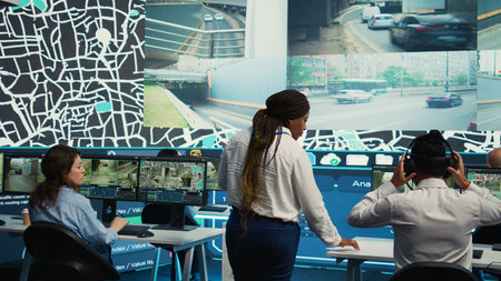 Team leader gives order tracking details to her employees in control center, people working together to guide delivery trucks on less busy routes. Using surveillance footage and gps. Camera B.の写真素材