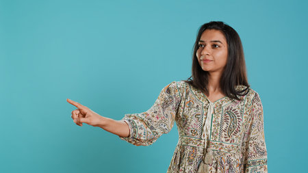 Indian woman showing copy text space, doing advertisement, isolated over studio background.の写真素材