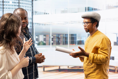 Clients and realtor touring a modern office space for relocation, reviewing modern property blueprints and plans. Business owner negotiating high class urban building investment strategy.の写真素材