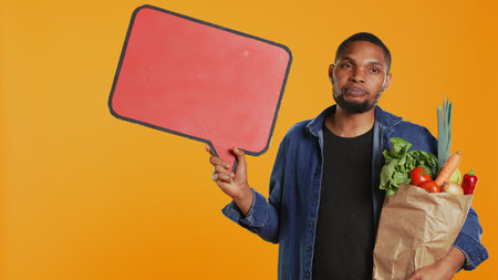 Young man showing a speech bubble empty cardboard sign to create an ad for sustainable lifestyle...