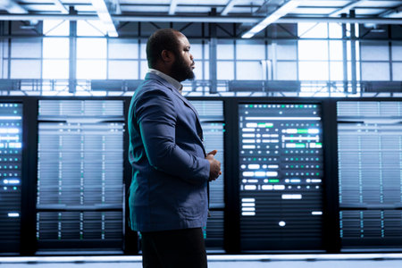 Engineer walking in data center, monitoring system performance, identifying bottlenecks and implementing optimizations to improve efficiency. Server room worker troubleshooting errorsの写真素材