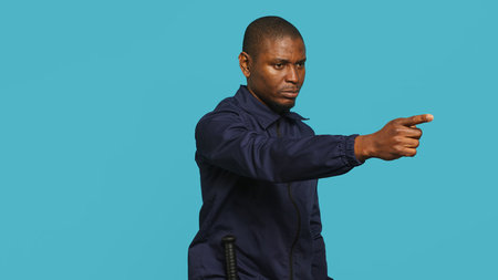 Security guard pointing finger at people to prevent them from gaining access in restricted areas. Portrait of stern bodyguard scolding and telling off unwanted visitors, studio background, camera Aの写真素材