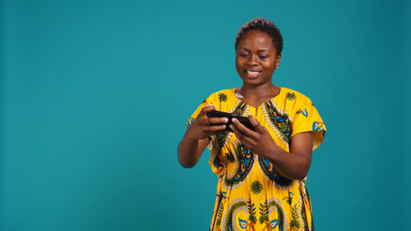 Happy pleased girl winning an online videogames competition, having fun playing e sport tournament against blue background. Woman plays internet gaming, celebrates her victory.の写真素材