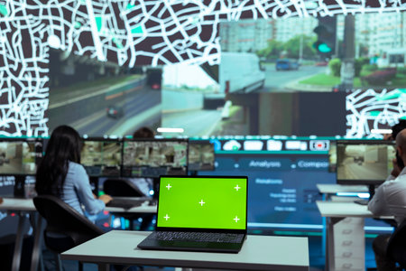Agency employees look at satellite map and CCTV footage in monitoring room, working with greenscreen display. People following delivery trucks in the city and gives directions for shipment location.の写真素材