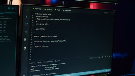 Extreme close up of software interface on PC screens showing lines of code running in empty room. Hacking malware programming script on displays, handheld camera shotの写真素材