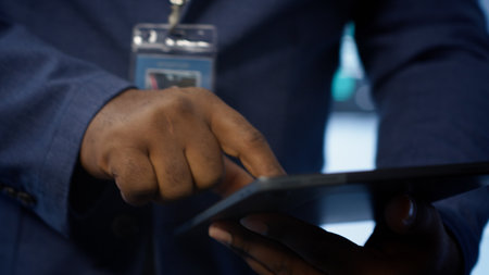 Technician in server hub checking recovery plan on tablet, monitoring energy consumption across mainframes. Close up shot of man in data center making sure rigs are functioning optimally, camera Aの写真素材