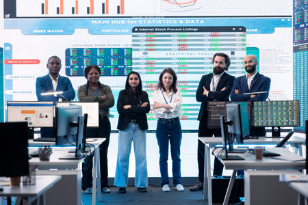 Diverse group of business professionals posing together in monitoring room, multinational company headquarters. Executive management team working with big data screen in the office.の写真素材