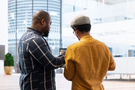 Real estate agent and client evaluating blueprints and discussing the architectural layout of the new office space during office tour. Businessman strategizing a corporate office relocation deal.の写真素材