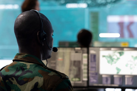 Military personnel operating on CCTV reconnaissance system in command post, gathering intelligence for an infantry unit to aid in battle. Satellite high tech operator in control room.の写真素材