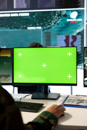 Military staff examines green screen display and reconnaissance footage, monitoring crucial radar information. Recruit works with CCTV surveillance imagery to aid troops in the field.の写真素材