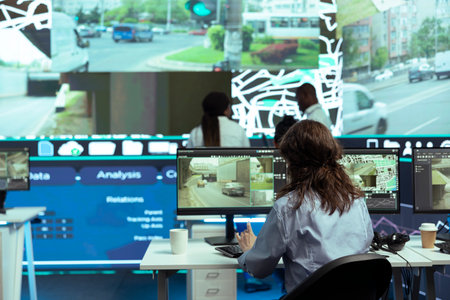 Call center operator monitors delivery trucks location on satellite map, tracking orders to ensure fast shipping service. Employee operating with surveillance footage on CCTV public system.の写真素材