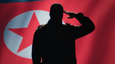 Conscript doing saluting hand gesture towards North Korea flag in command center, showing respect. Military unit in uniform serving in Korean Peoples Army, doing honoring gesturing, camera Aの写真素材