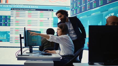 Enterprise colleagues reviewing project updates and details in monitoring room, establishing budget and other resources to achieve strategic business goals. Multiple corporation operations. camera B.の写真素材