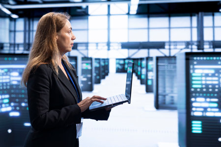 IT staff member walking in data center, using laptop to configure network infrastructure such as...