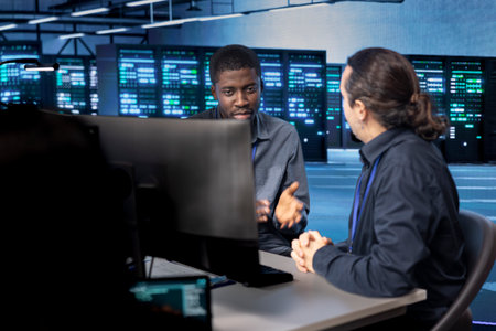 System administrators reconfiguring server room to optimize it for data processing requirements of customers. IT experts ensuring data center equipment operates efficiently, doing maintenanceの写真素材