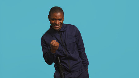 Cheerful security guard celebrating achievements during protection job shift. Portrait of joyous bodyguard feeling satisfied after completing tasked orders, studio background, camera Bの写真素材