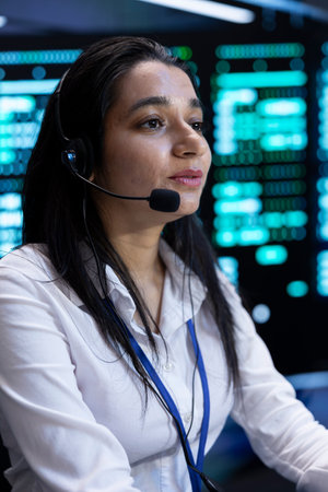 Data center call center admin responsible for providing logistics support to customers. Woman in server hub overseeing infrastructure systems and communicating with engineersの写真素材