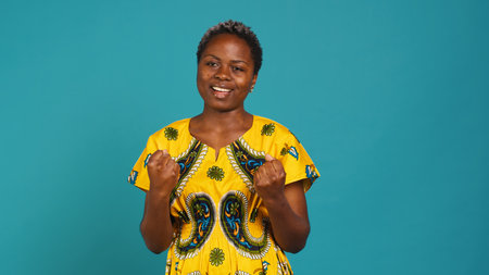 Cheerful woman hoping for something good to happen to her, cheering and feeling hopeful in studio. Positive smiling young adult posing with confidence against background. Camera A.の写真素材