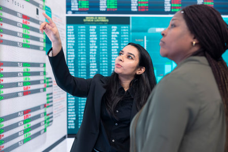 Diverse team of employees examine infographics on a big screen to evaluate supply and demand, ways...