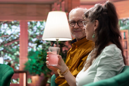 Senior man and woman drinking their fizzy effervescent vitamins with glasses of water, enjoying the fresh taste of the wellness supplement. Old couple serve daily dose of dissolved .の写真素材