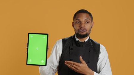 Waiter showing a tablet with isolated copy space in studio, working in a service oriented environment and catering industry. Friendly restaurant staff serving clients at their tables. Camera A.の写真素材