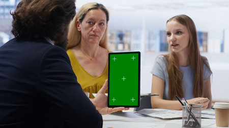 People receiving personalized financial plan from financial advisor using isolated screen tablet. Customers learn how to make profitable decisions from agent using chroma key device, camera Bの写真素材
