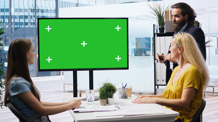 Broker in office offering financial advice to clients, looking at forex index values on green screen display. Financial advisor analyzing customers market shares on chroma key device, camera Aの写真素材