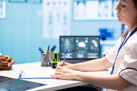 Physician writing a prescription with the recommended treatment and supplements for wellness, giving instructions and medical advice to patient. Prescribe medication on insurance. Close up.の写真素材