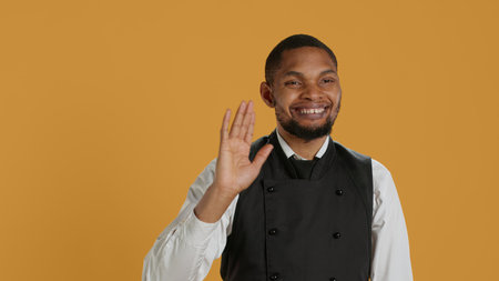 Skilled waiter waving and greeting clients at five star restaurant, working in hospitality industry and catering. Employee server welcoming customers to eat, professionalism. Camera A.の写真素材