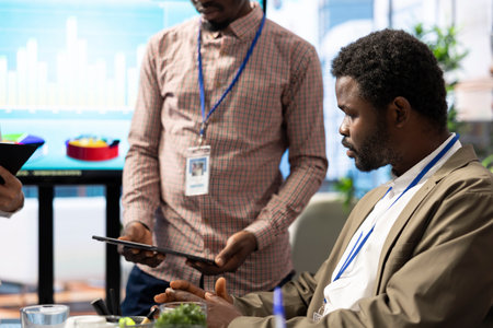Team of business associates reviewing statistics and infographics on a tablet, working together to gather insight for enterprise development. Employees discussing legal changes at a meeting.の写真素材